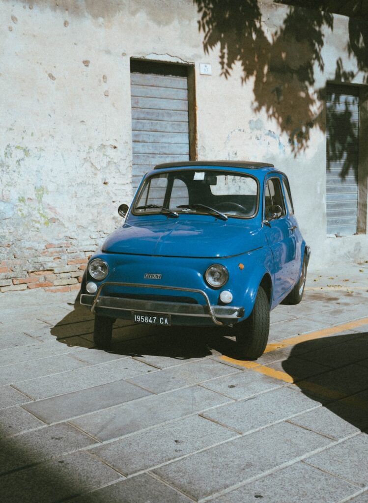 a small blue car parked in front of a building